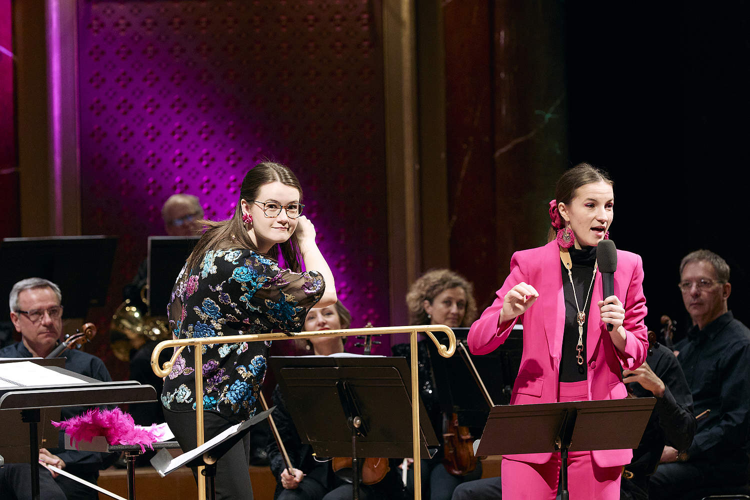 © Dougados Magali Aldo's Carnival family concert with conductor Zofia Kiniorska and saxophonist and artist in residence with the Orchestre de la Suisse Romande Valentine Michaud, speaking in a microphone on the Victoria Hall stage.